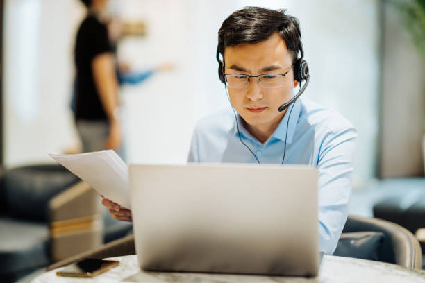 istock Asian businessman on videoconference with headset in modern office, capture the serious and contemplative emotions. 2166417008