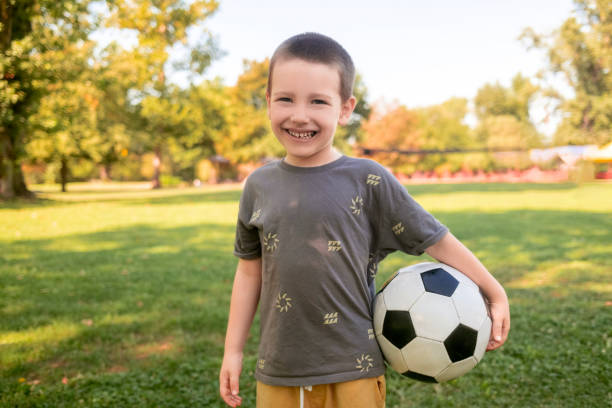 istock Boy Posing with Football on the Grass 2166418710