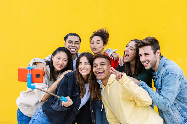 istock Happy young friends taking photo using smart phone and selfie stick 2166426004