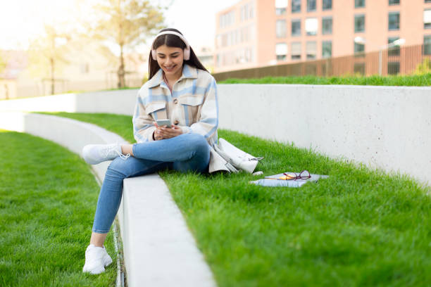 istock Young girl using smartphone and headphones in park 2166429651