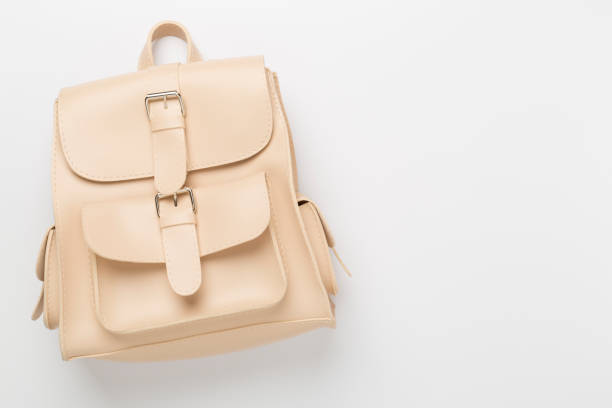 Beige stylish backpack on color background, top view.