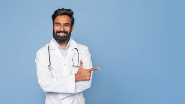 istock Friendly Doctor Pointing With Stethoscope Against Blue Background 2166431951
