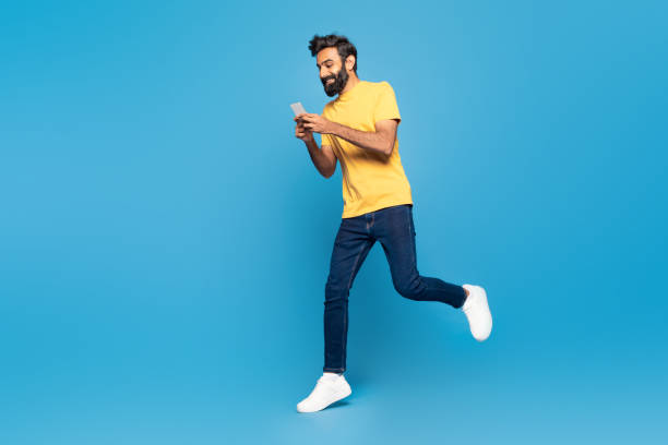 istock Man in Yellow Shirt Running While Looking at Cell Phone 2166431978