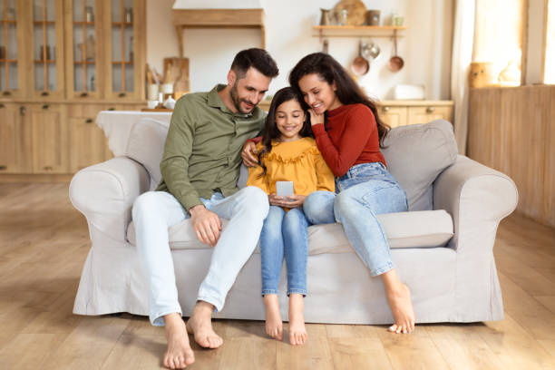 istock Family viewing phone together on couch at home 2166434821