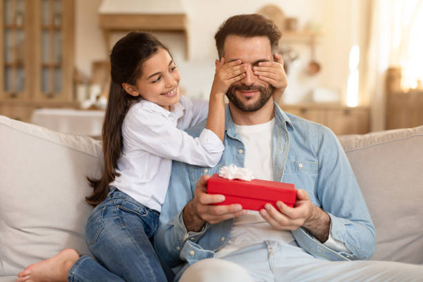 istock Daughter covering father's eyes, gift in her hand 2166434852