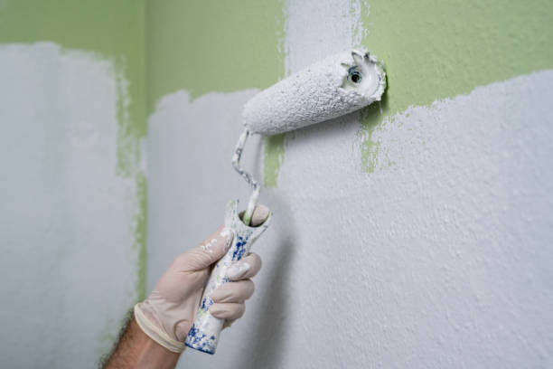 istock A man's hand paints a green wall in  room with a roller in white paint. Construction work and cosmetic repairs in house, painting walls, tinting, finishing work with your own hands. 2166444111
