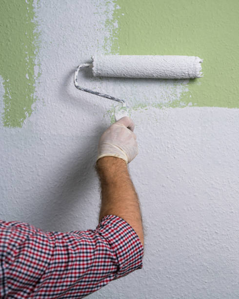 istock A man's hand paints a green wall in  room with a roller in white paint. Construction work and cosmetic repairs in house, painting walls, tinting, finishing work with your own hands. 2166444117
