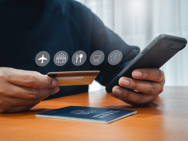istock Travel payment plan, icon on credit card in businessman hand while using smart mobile phone to purchase on app for flight and hotel booking and passport on wooden table. International trip concept. 2166444506