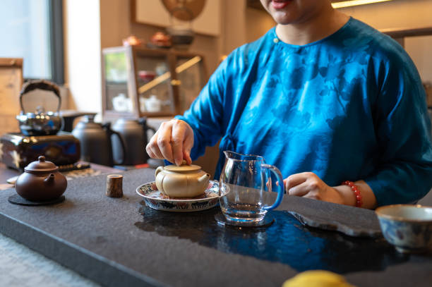 istock Person covering the teapot lid during a tea preparation ritual process. 2166447289