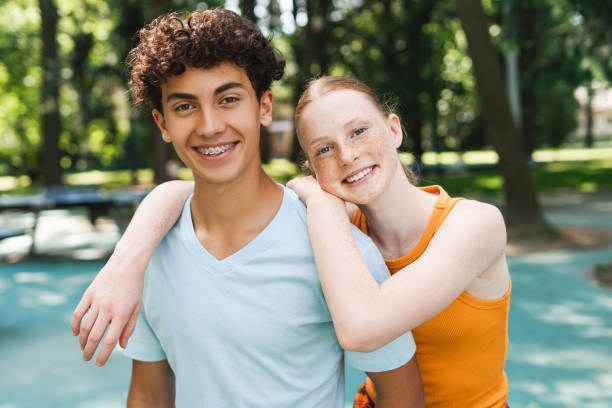 Portrait of attractive red hair girl embracing her male friend outdoors Portrait of happy red hair teenager girl hugging her male friend at the park. Children friendship concept little redhead girl stock pictures, royalty-free photos & images