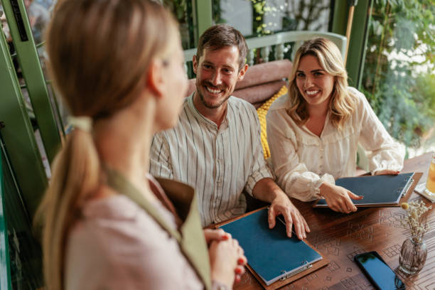 istock Couple looking up at a waitress and smiling 2166457373