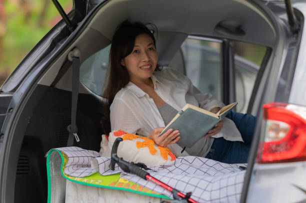 istock Asian Chinese Female Car Camping resting inside the car while reading book 2166457456