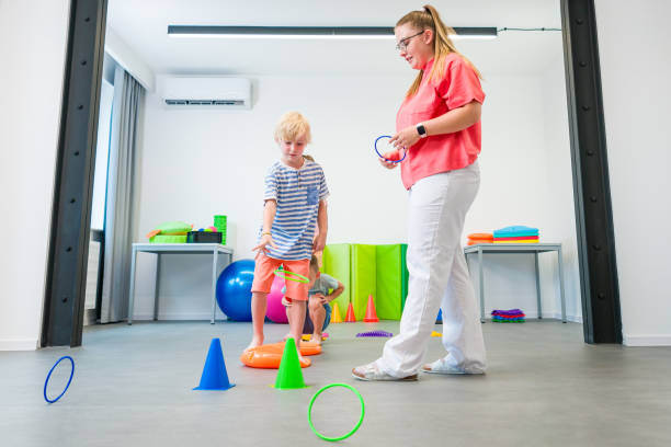 istock Kids group physio therapy. Children and physical therapist exercising during session. Bilateral coordination or integration is the ability to use both sides of the body together in a coordinated way. 2166459862