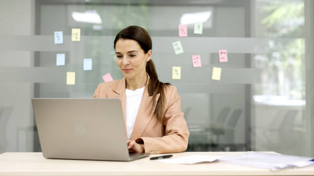 istock Confident business woman using laptop in modern office. Her professional demeanor indicates that she has important discussions with clients. 2166461420