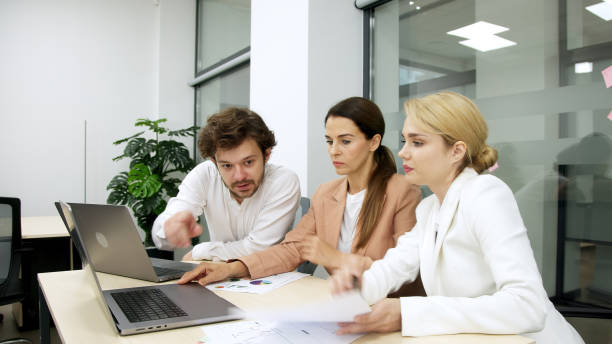 istock Business team in a modern office using a laptop for financial analysis. They brainstorm and discuss a corporate project, collaborating on solutions. Perfect for teamwork and financial strategy themes. 2166461505
