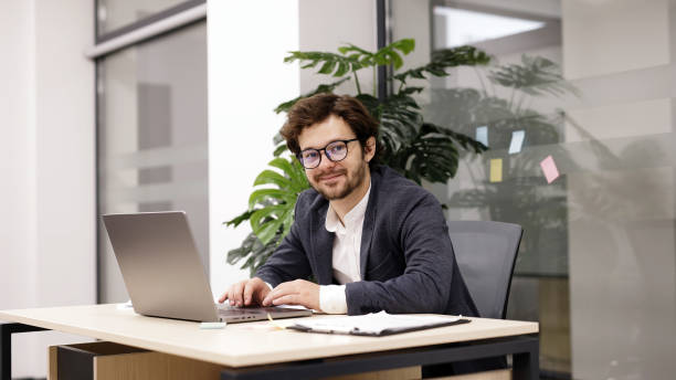 istock A young trader with a beard is focused on his laptop in a modern office. Ideal for showcasing finance and trading activities. 2166461815