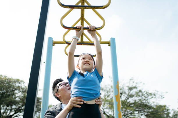 istock Father supports daughter as she hangs from climbing frames 2166462874
