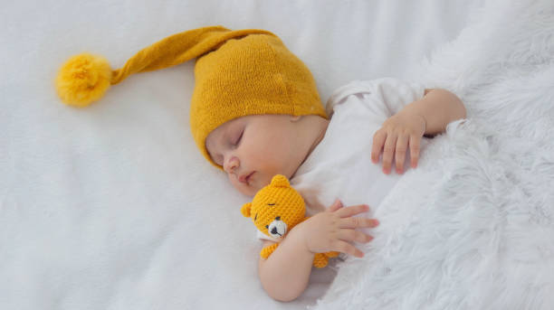 istock A newborn baby is sleeping on a white background hugging a yellow teddy bear 2166463262