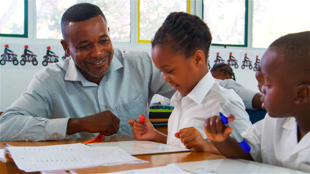 istock Teacher Assisting Students With Worksheets in Classroom During Daytime 2166470824