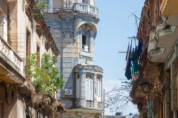 Havana, Cuba - August 7, 2024: Architecture of building exterior on a residential district. Weathered and run-down structures are seen in the blue sky scene.