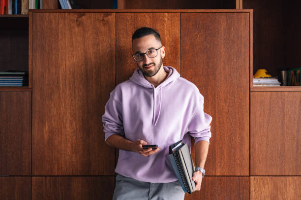 Student Texting and Holding Books in a Library