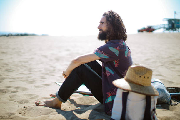 Surfer relaxing next to the ocean in Venice, California. Slow life, surfing lifestyle concepts, summertime joy at the ocean.