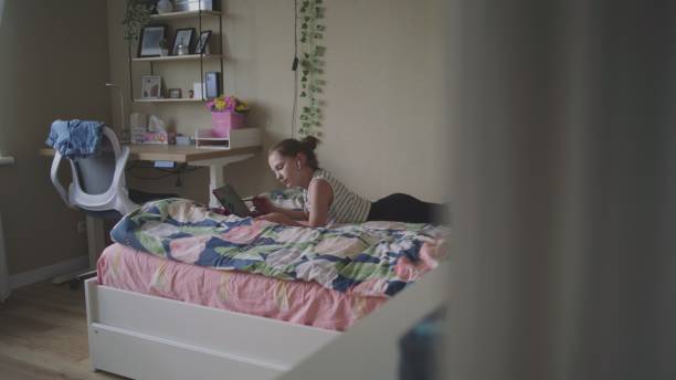 istock Young girl lies on cozy bed and uses digital tablet computer 2166485431