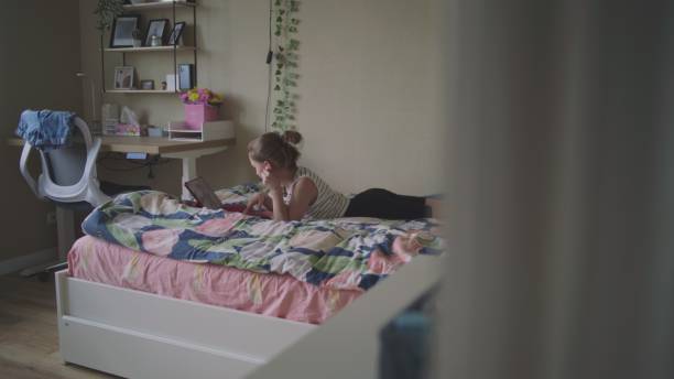 istock Young girl lies on cozy bed and uses digital tablet computer 2166485508