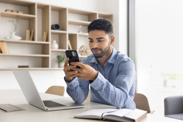 istock Focused young Arab manager working online, typing on mobile phone 2166486188