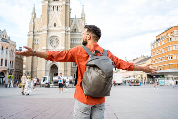 Young happy man tourist with arms outstretched in the city
