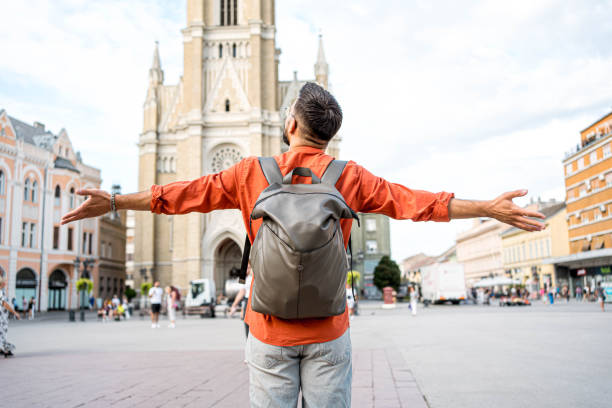 Young happy man tourist with arms outstretched in the city