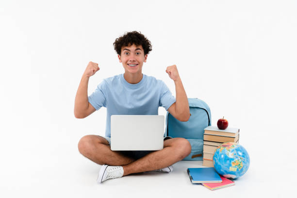 istock Happy boy winner pupil student using laptop winning gesture celebrating having success isolated 2166489106