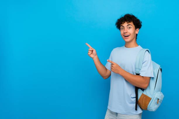 istock Smiling boy pupil student with dental braces backpack pointing index finger copy space isolated 2166489558