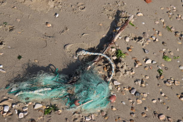 Green fishing net polluting a beach with small pebbles, showing the impact of pollution on the environment
