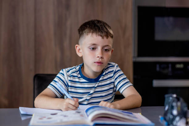 istock Schoolboy boy writes lessons in the kitchen 2166493686