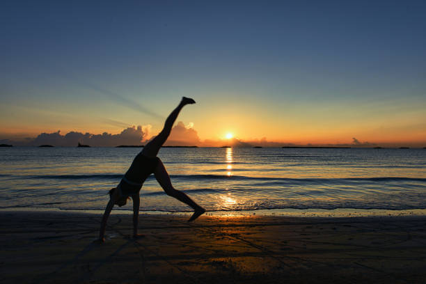 A woman performs cartwheels on the beach at dawn in the Italian Adriatic Sea
