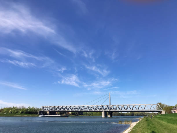 A bridge spans a river with a clear blue sky above. The bridge is a large structure that connects two sides of the river