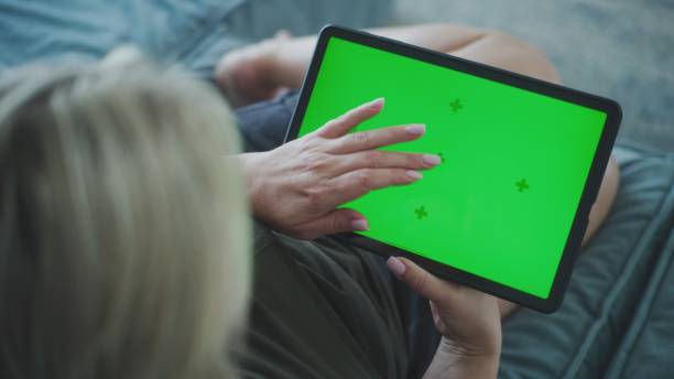 istock Back view of woman holding tablet computer with green screen 2166496895