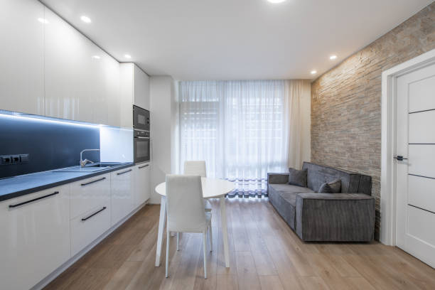 istock Scandinavian Style Cozy Modern Open Bright Kitchen Home Interior. Oven, Faucet, Fridge, Microwave. White Color. Dining Table, Hardwood Floor. Windows and Curtains. Sofa Couch 2166497850