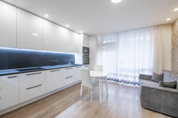 istock Scandinavian Style Cozy Modern Open Bright Kitchen Home Interior. Oven, Faucet, Fridge, Microwave. White Color. Dining Table, Hardwood Floor. Windows and Curtains. Sofa Couch 2166497974