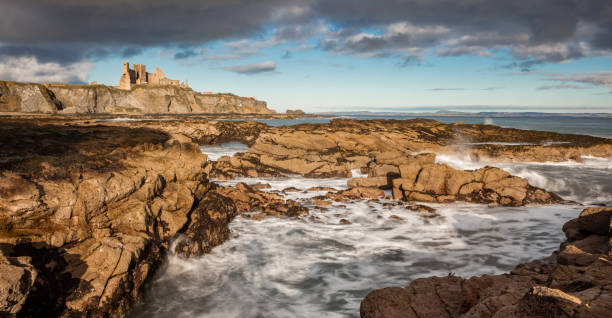 Tantallon Castle, Scotland, on a cliff by the sea, with waves crashing against rocky shore Ruins of Tantallon Castle near North Berwick, Scotland, on a cliff by the sea, with waves crashing against rocky shore and blue sky with clouds north berwick scotland east lothian castle scotland stock pictures, royalty-free photos & images