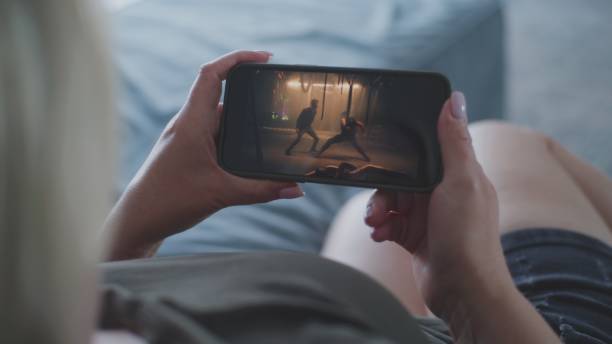 istock Woman watches action movie using smartphone while lying on sofa 2166500973