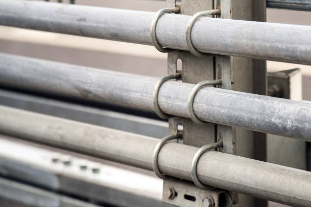 metallic pipes secured to a pole with curved threaded brackets, highlighting the interplay of industrial design and functionality