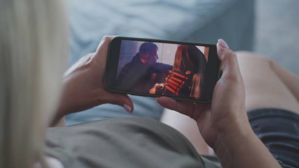 istock Woman watches action movie using smartphone while lying on sofa 2166504407