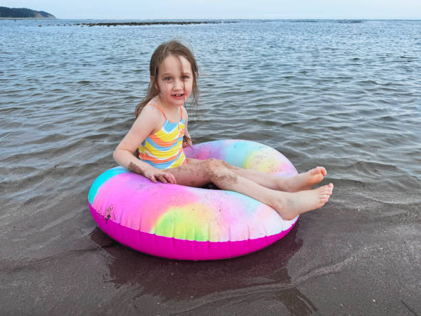 A young girl enjoys tubing at a beach.