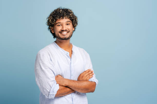 istock Young indian man smiling with folded arms on blue background 2166513306