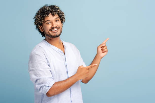 istock Happy Indian young man pointing at something on blue background 2166513325