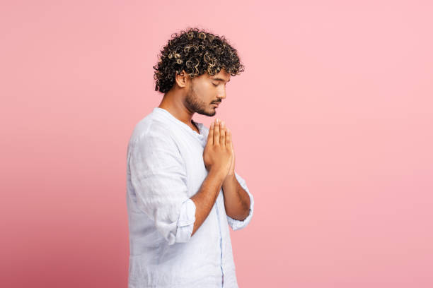 istock Pensive man praying with hands together on pink background 2166513373