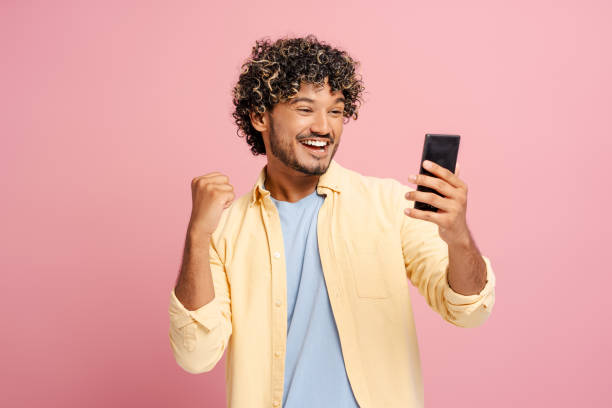 istock Excited young man celebrating success while reading a text message on smartphone 2166513380