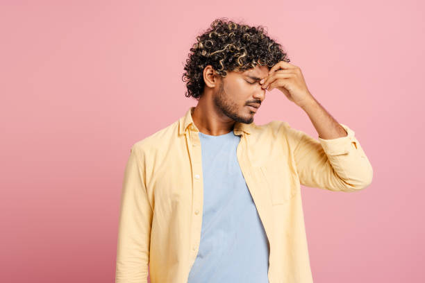 istock Young Indian man suffering from headache touching his temples on pink background 2166513424